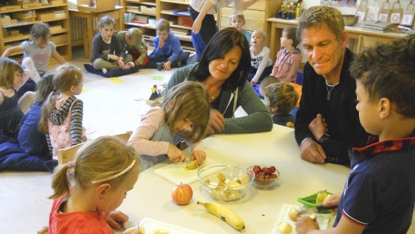 KiGa- Leiterin Ulrike Bauer mit GR Erich Auer mit Kindern beim Obstschneiden für die gesunde Jause