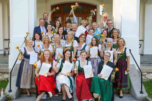 Strahlende Absolventinnen der Allgemeinen Gesundheits- und Krankenpflege an der GuKPS Bad Ischl, umrahmt von ihren Gratulant/-innen