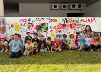 Kindergartenkinder bemalten Betonwand im Garten des Seniorenheims