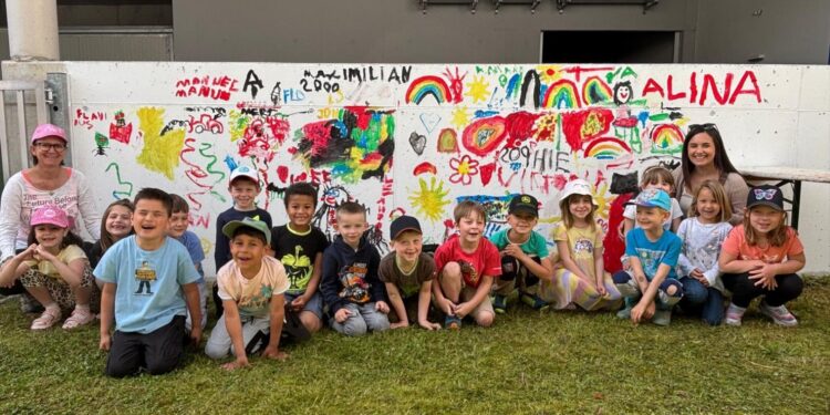 Kindergartenkinder bemalten Betonwand im Garten des Seniorenheims