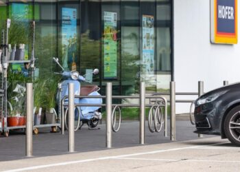 Kind auf Parkplatz vor Geschäft mit Fuß in Fahrradständer eingeklemmt