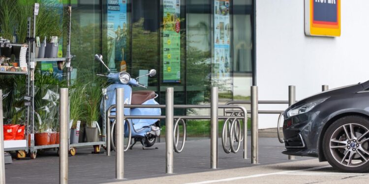 Kind auf Parkplatz vor Geschäft mit Fuß in Fahrradständer eingeklemmt