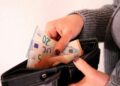 a woman is holding a wallet full of money