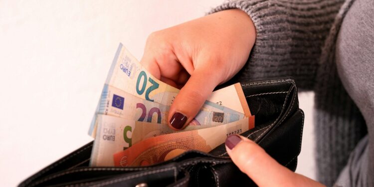 a woman is holding a wallet full of money
